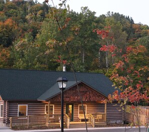 A log cabin with a porch, a chimney, and a street lamp in front. - Rippling River Resort (Marquette)