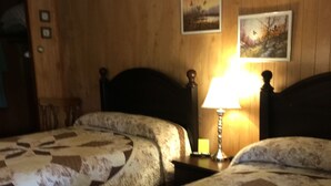 A hotel room with two beds, wooden paneling on the walls, and two framed pictures. - Cave Mountain Motel (Windham)