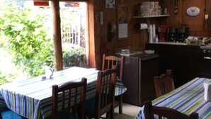 A kitchen with wooden cabinets, a refrigerator, and a window overlooking greenery. - Cave Mountain Motel (Windham)