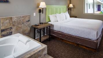 A hotel room with a large bed, a separate bathroom with a bathtub, and a window providing a view of the outside.