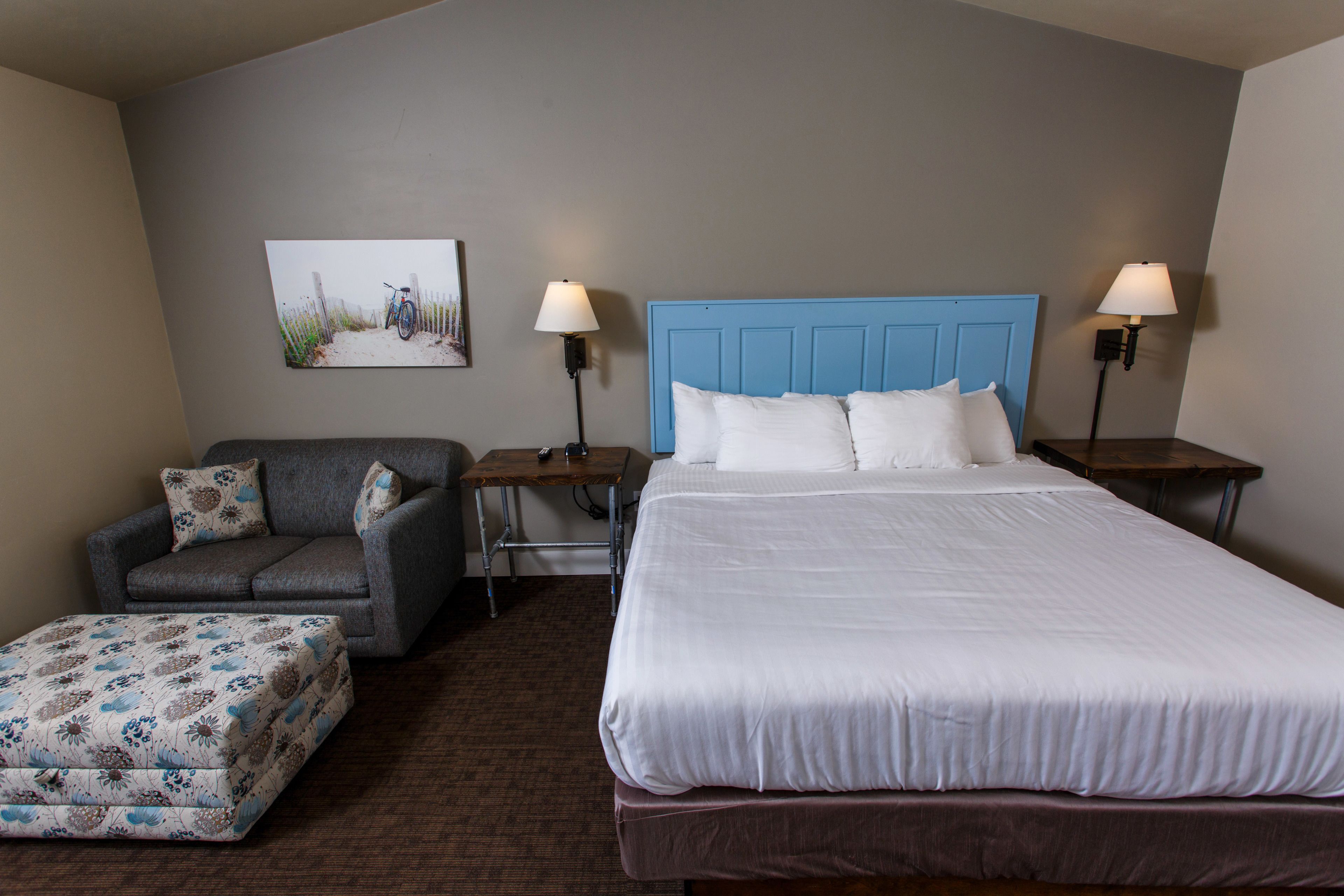 Une chambre d’hôtel avec un lit, une chaise, une petite table et une lampe.
