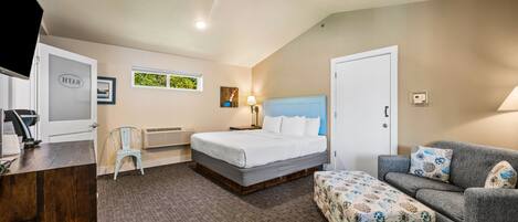 A hotel room with a bed, a sofa, a desk, and a chair.