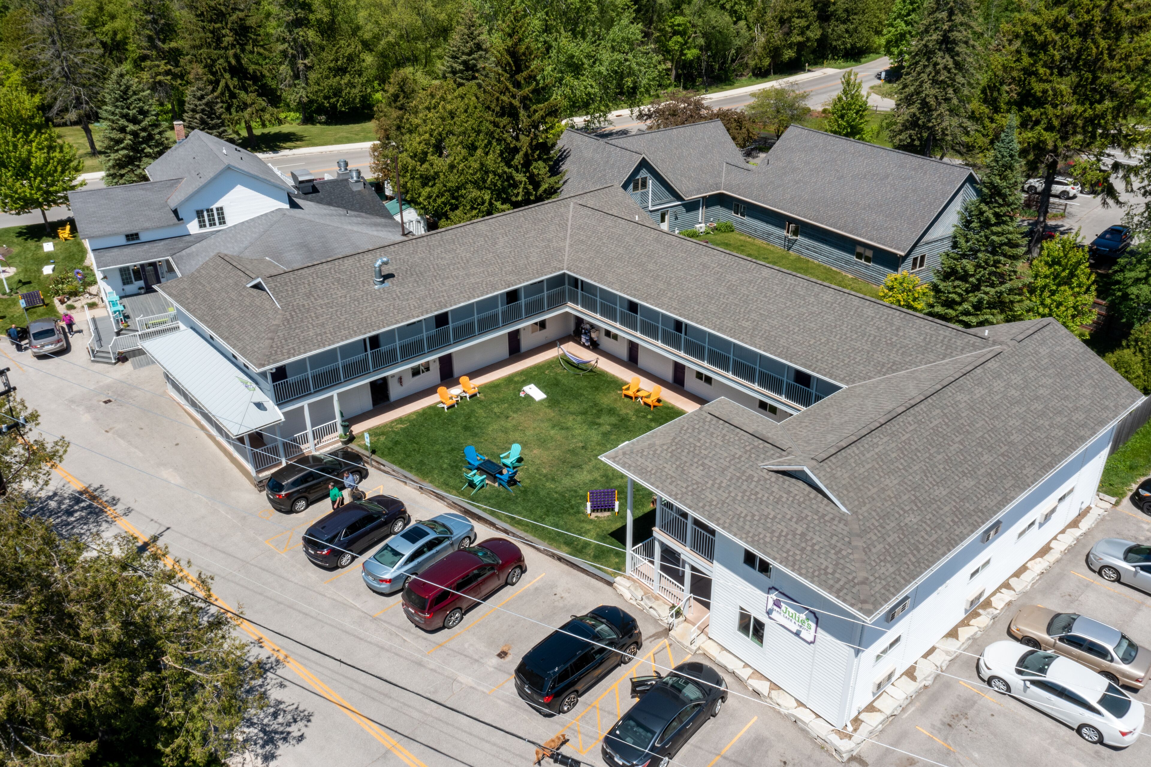 An aerial view of a building with a parking lot, a grassy area with outdoor furniture, and a flag.