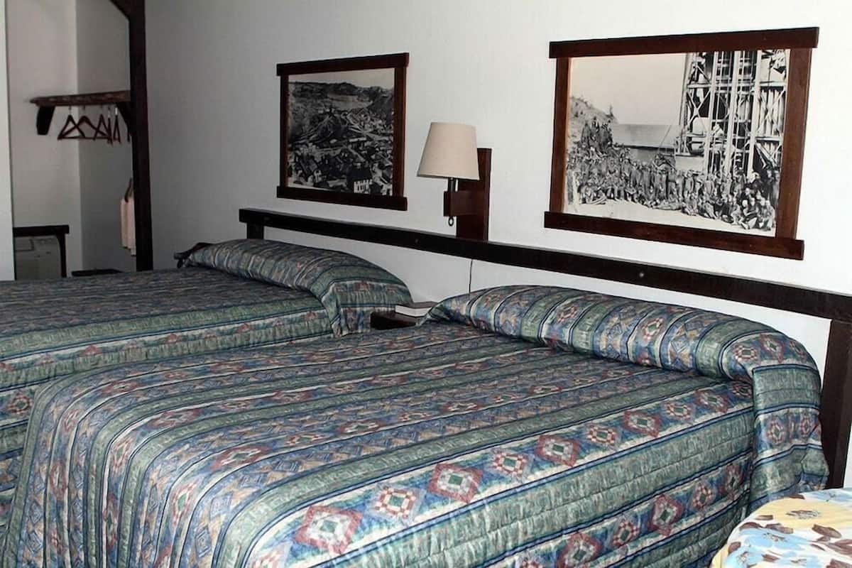 A double bed with patterned bedding, a bedside lamp, and two framed pictures on the wall.