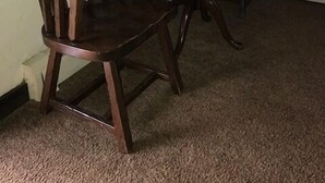 A dining area with a table and two chairs, a window with curtains, and a carpeted floor. - Bunkhouse Motel (Guernsey)