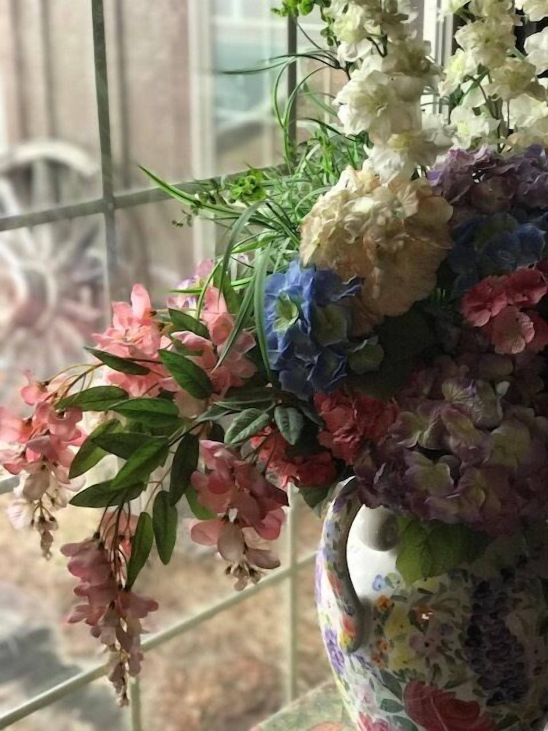 A floral arrangement in a decorative vase on a windowsill.
