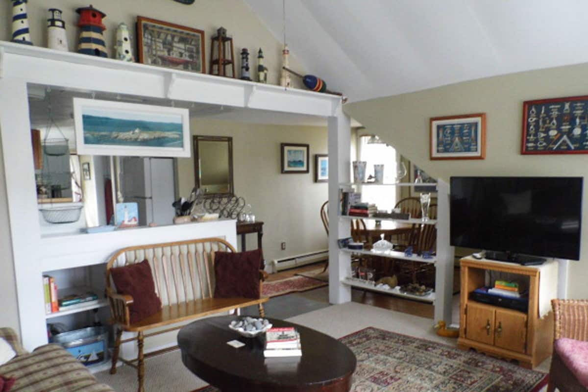 A living room with a sofa, a coffee table, a television, and a bookshelf.
