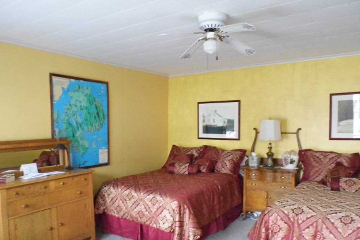 A room with a bed, a dresser, a nightstand, and a ceiling fan.