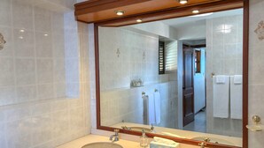Un baño con dos lavamanos, un espejo grande y techo de madera.
