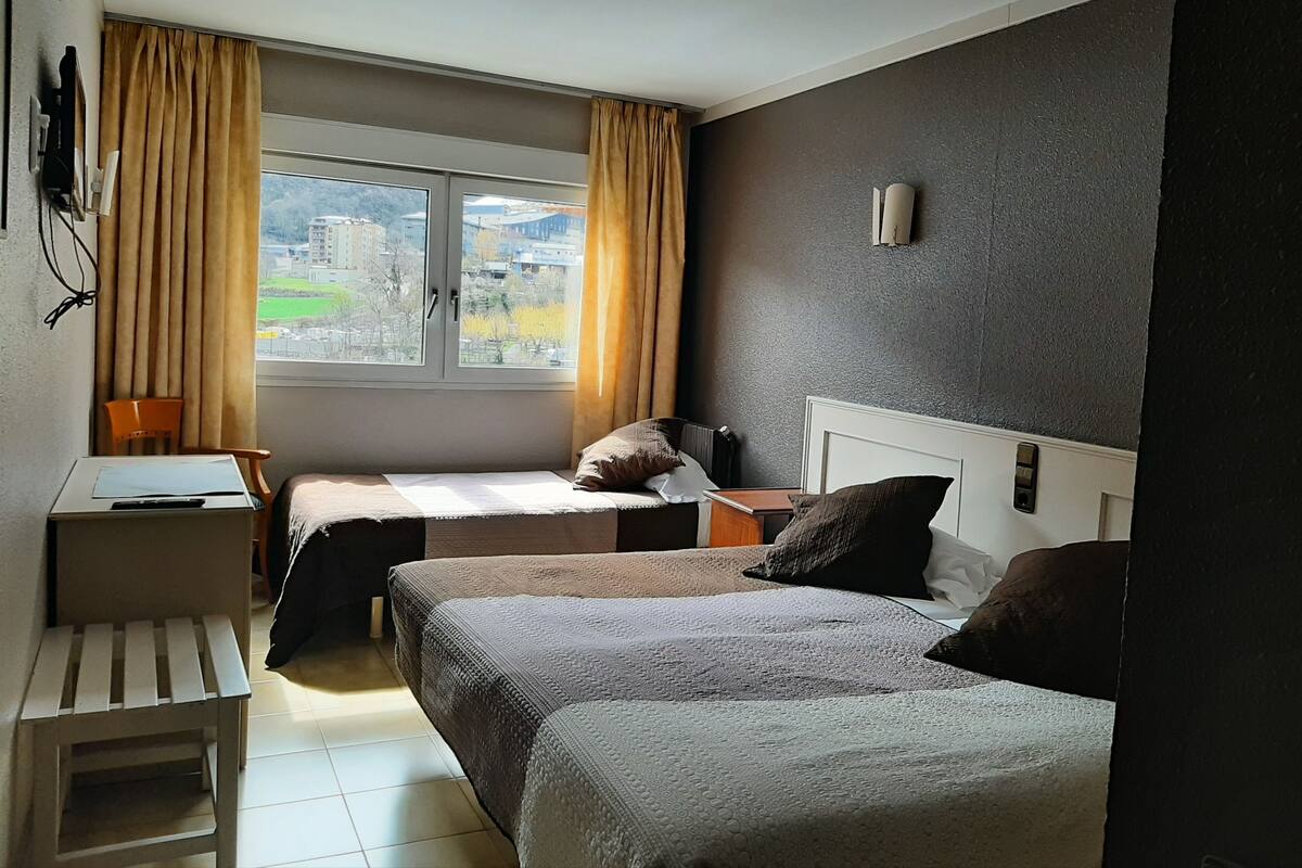 A hotel room with two beds, a desk, and a chair.