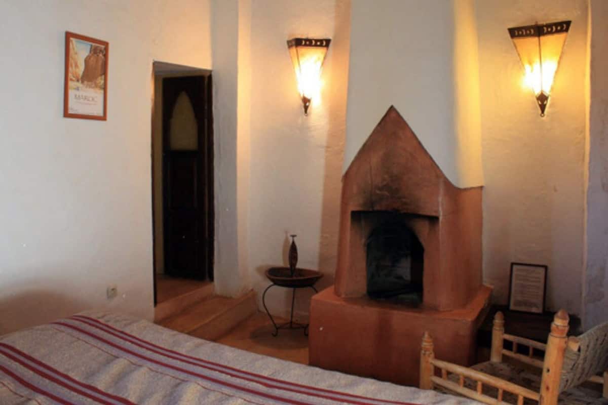 A room with a fireplace, a bed, and two wall-mounted lights.