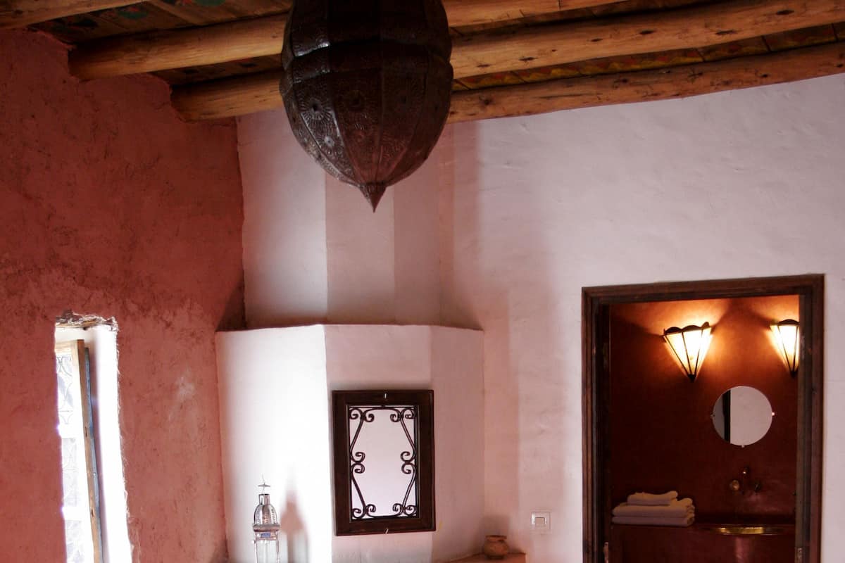 A room with a fireplace, a mirror, a window, and a door leading to another room.