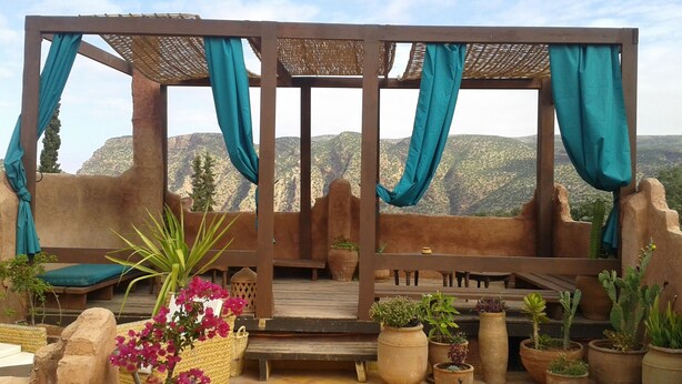 A covered outdoor seating area with a view of a mountainous landscape. - Riad Cascades d'Ouzoud (Ait Taguella)