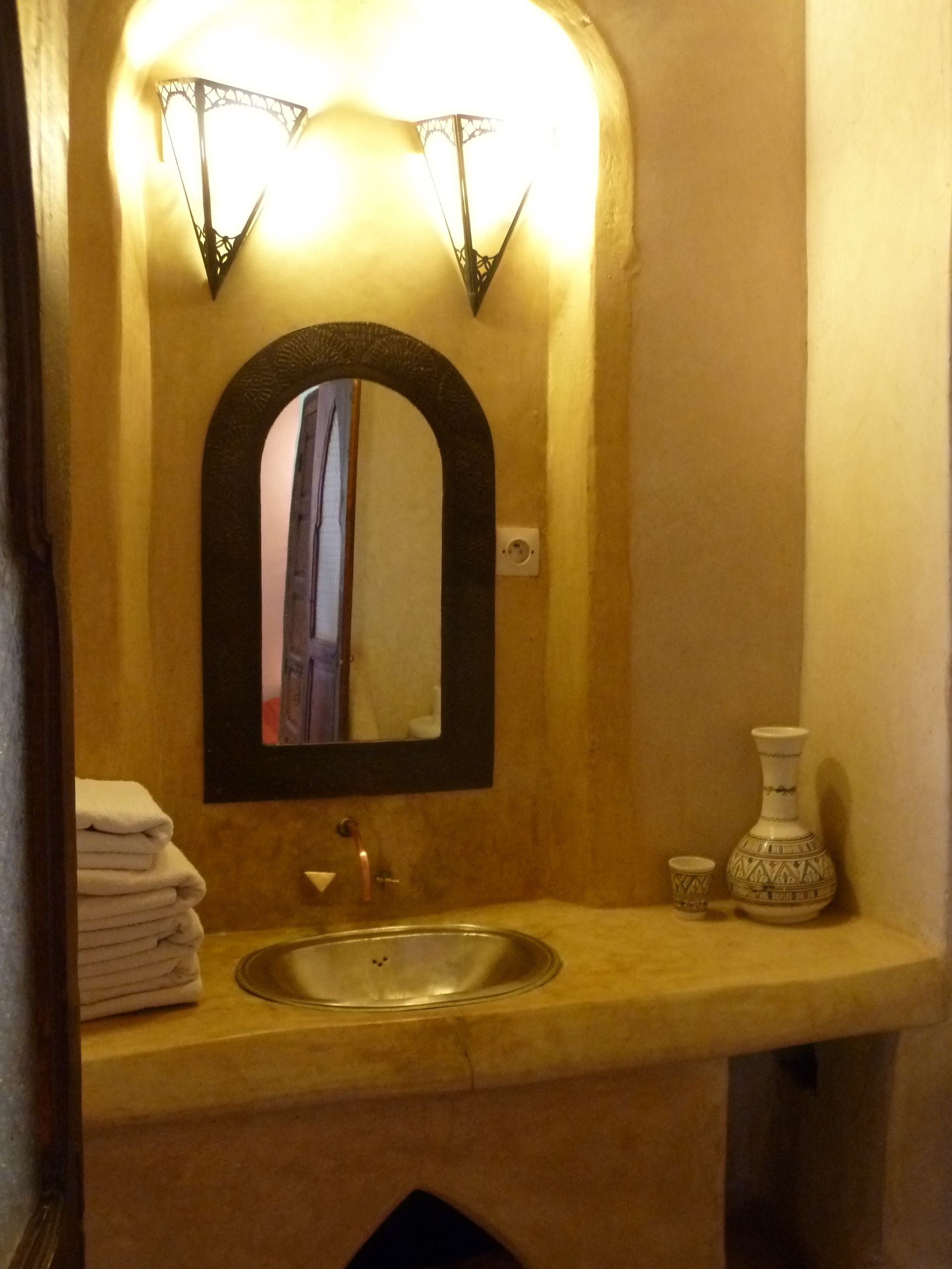 Un baño con lavamanos, espejo y toallero.