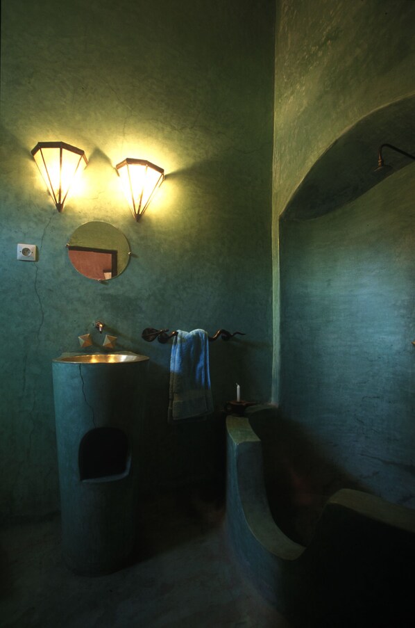 Une salle de bain équipée d’un lavabo, d’un miroir et de deux appliques murales.