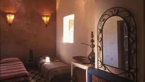A cozy room with a fireplace, two beds, a mirror, and patterned walls. - Riad Cascades d'Ouzoud (Ait Taguella)