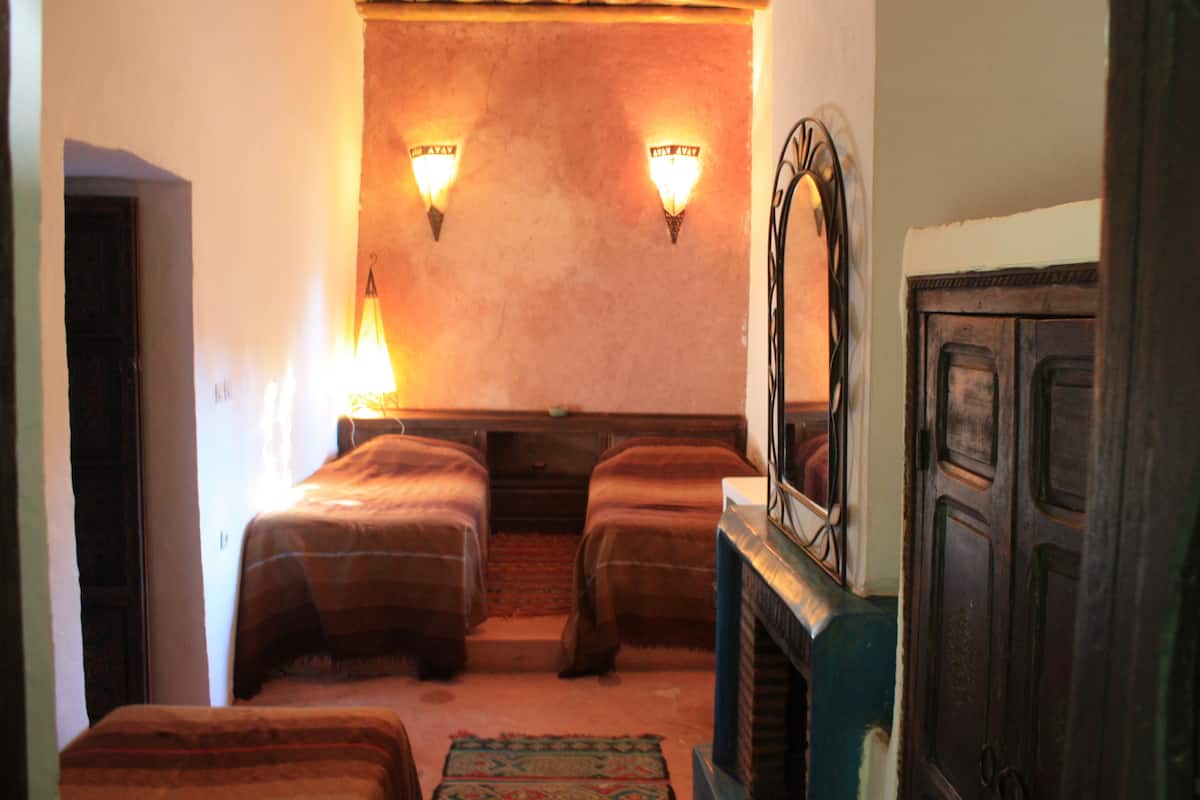 A room with two beds, a fireplace, and wall-mounted lights.