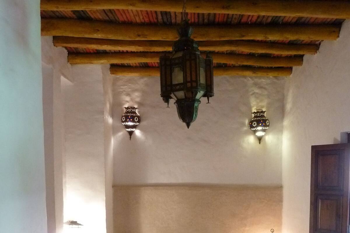 A room with a bed, two wall-mounted lights, and a hanging lantern.