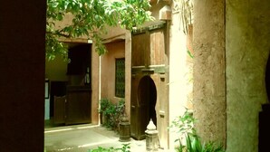 A courtyard with a wooden door, a small fountain, and potted plants. - Riad Cascades d'Ouzoud (Ait Taguella)