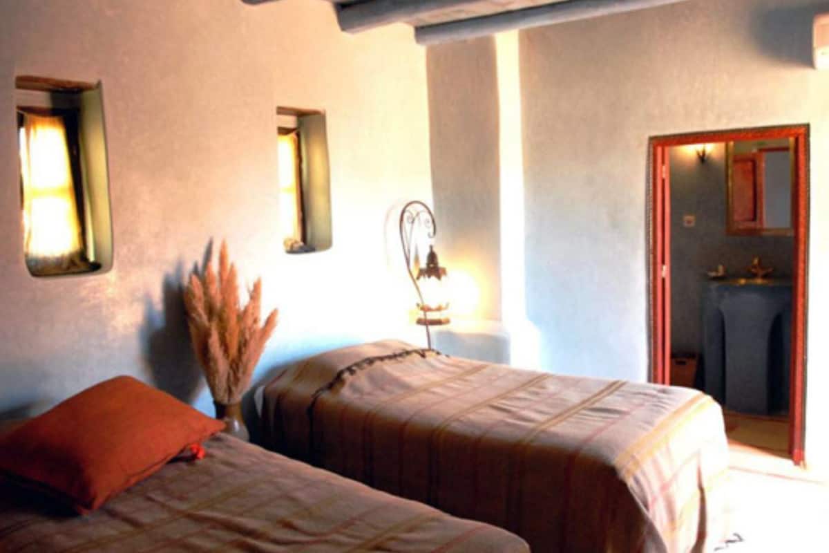 A bedroom with two beds, a mirror, and a window.