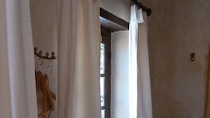 A bathroom with white curtains, a towel rack, and a woven basket on a ledge. - Riad Cascades d'Ouzoud (Ait Taguella)