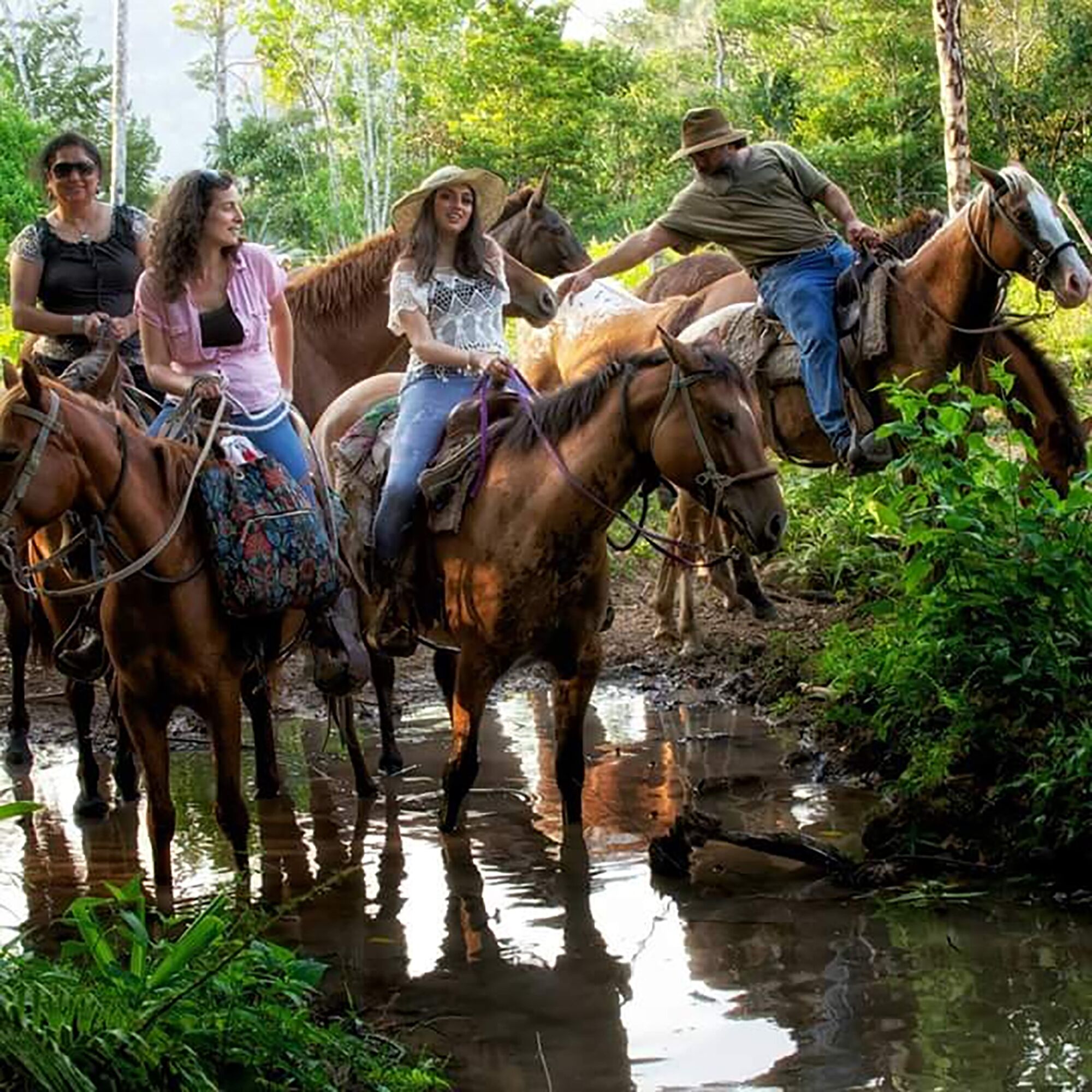 A group of people riding horses along a riverbank.