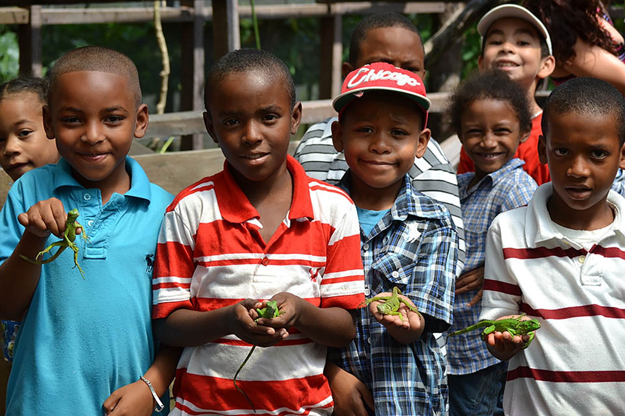 A group of children holding small lizards.