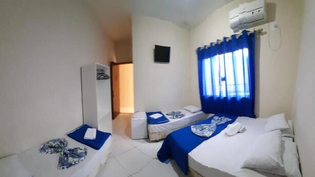 Een hotelkamer met twee éénpersoonsbedden, een klein tafeltje, een stoel en een airconditioner.
