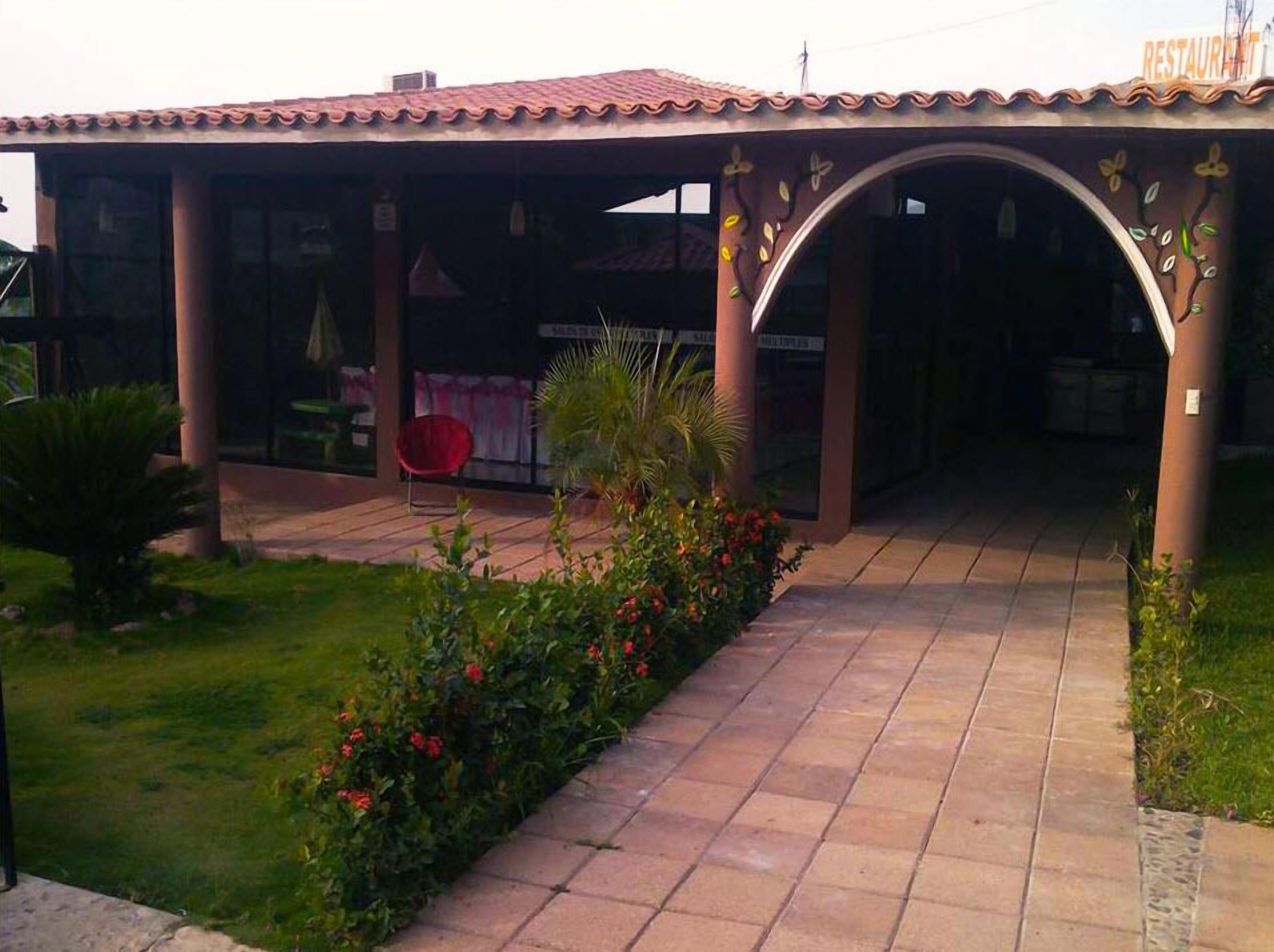 A covered patio area with a tiled floor, a red chair, and a small table.