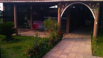 A covered patio area with a tiled floor, a red chair, and a small table.