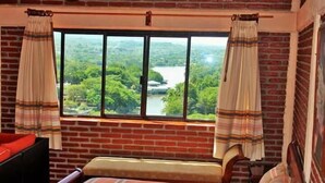 A room with a bed, a bench, and a window with curtains. - River Side Hotel (Chiapa de Corzo)