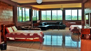 A spacious bedroom with a large bed, a sofa, and a view of the mountains. - River Side Hotel (Chiapa de Corzo)