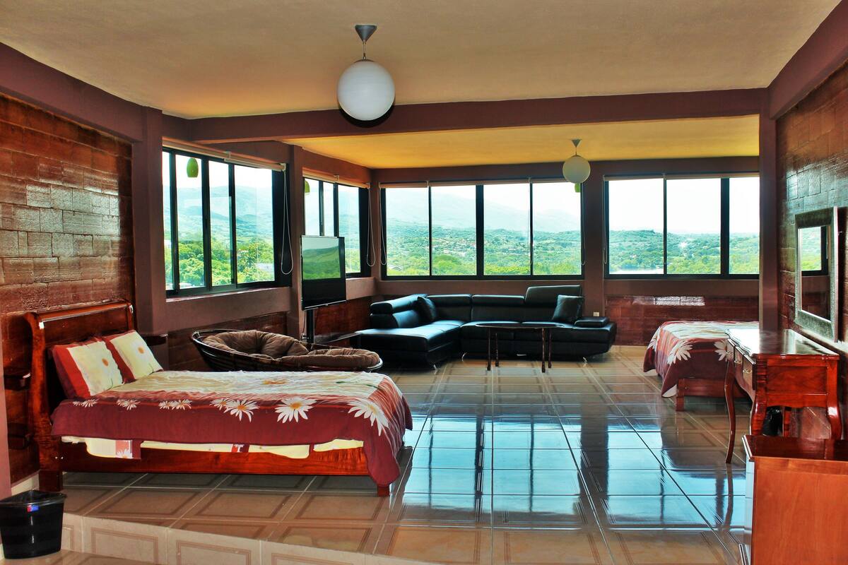 Un dormitorio espacioso con una cama grande, un sofá y vistas a la montaña.