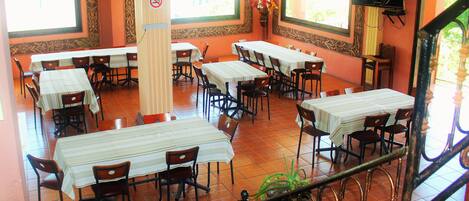 A restaurant with multiple tables and chairs, a staircase, and large windows.