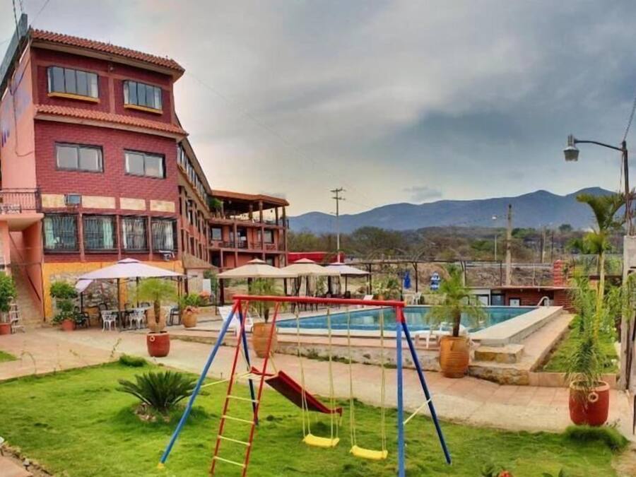 Un hotel con piscina, zona de juegos para niños y vistas a la montaña.