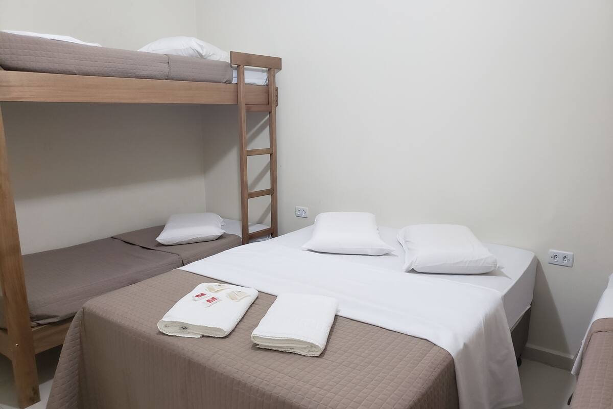 Une chambre de dortoir avec des lits superposés, un lit simple et une petite table avec des serviettes.