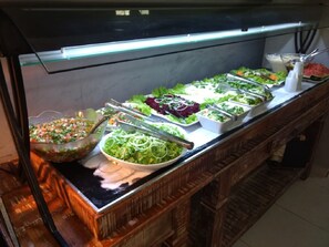 Buffet com diversas saladas e uma fatia de melancia.