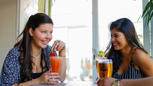 Two people sitting at a table with drinks, one with a glass of red beverage and the other with a glass of amber beverage. - Hotel Ciudad del Sol (Termas de Rio Hondo)