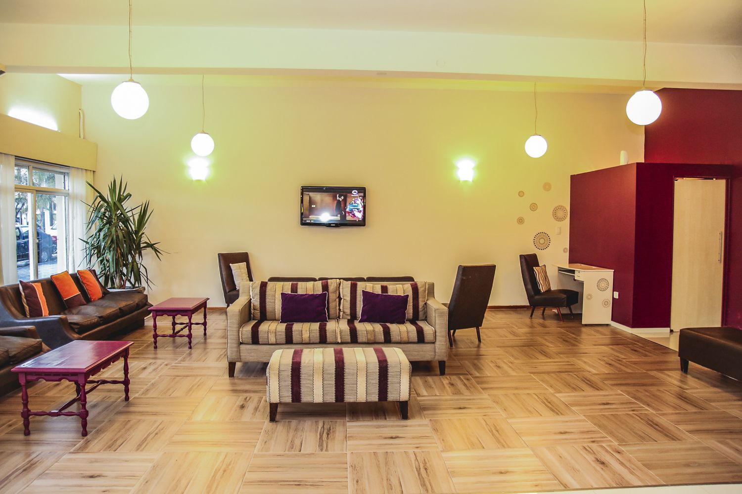 A spacious living area with a sofa set, a coffee table, and a TV mounted on the wall.