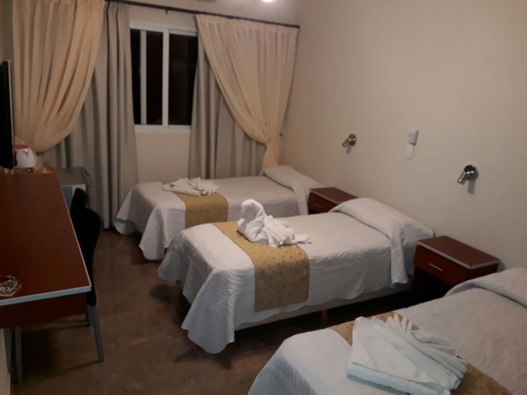 Een hotelkamer met twee bedden, een bureau en een raam met gordijnen.