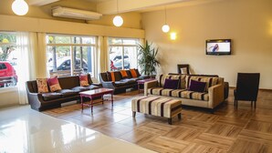 A spacious lobby with multiple seating areas, large windows, and a flat-screen TV on the wall. - Hotel Ciudad del Sol (Termas de Rio Hondo)