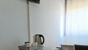 Una kitchenette compacta con un refrigerador, una tetera y una cafetera sobre la encimera.