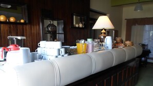 Una barra de desayuno con una variedad de tazas, vasos y una cafetera.
