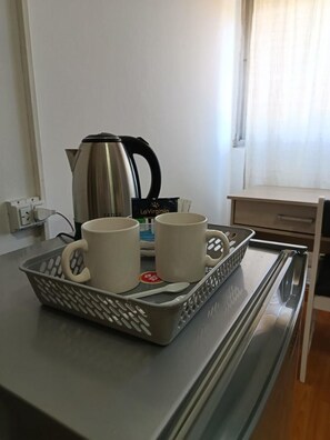 A kitchen counter with a kettle, two mugs, and a tray with a spoon. - Hotel Iberia (Neuquén)