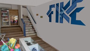 A staircase with a glass display case at the bottom and a large blue logo on the wall. - Hotel Fike (Bucaramanga)