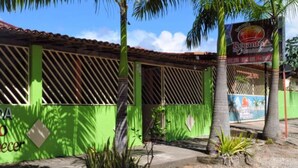 Un edificio con fachada verde y un letrero que dice 'POUSADA Recanto do Ananheirocer'.
