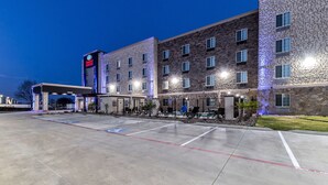 Un hotel con fachada de ladrillo moderno, un acceso cubierto y un estacionamiento con espacios demarcados.