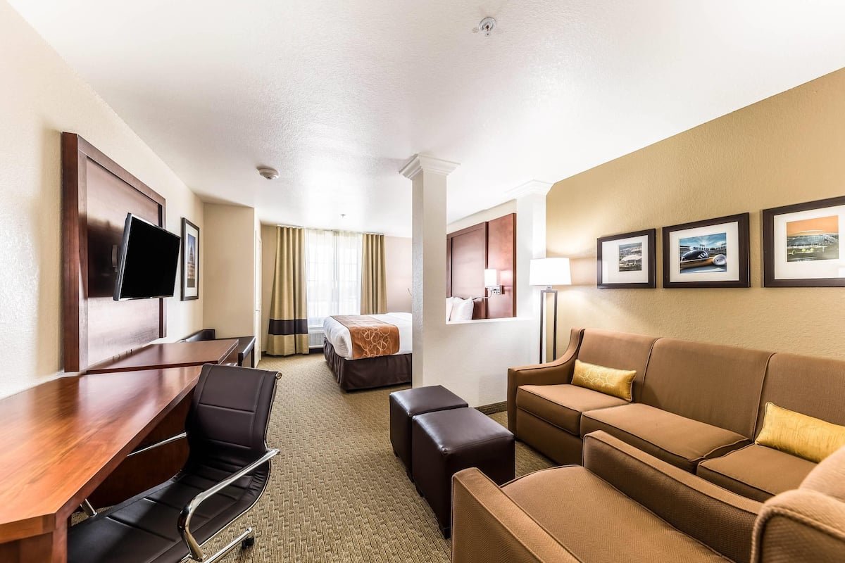Una habitación de hotel con cama, escritorio, sofá y televisión.