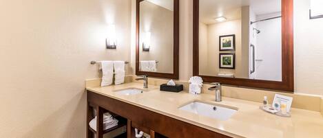 A hotel bathroom with two sinks, a large mirror, and a towel rack.