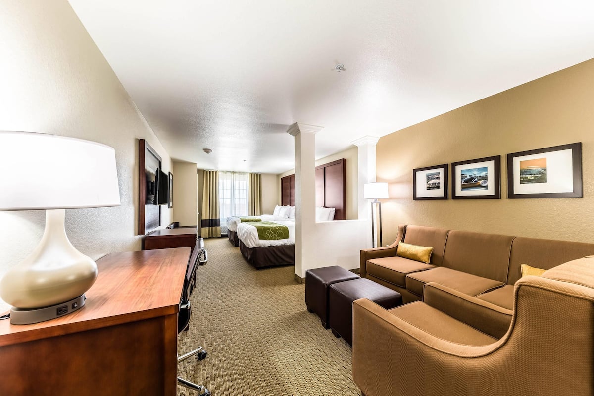 Una habitación de hotel con cama, sofá, escritorio y lámpara.